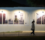 사진이 전시된 외부 전시 벽을 지나가는 관람객