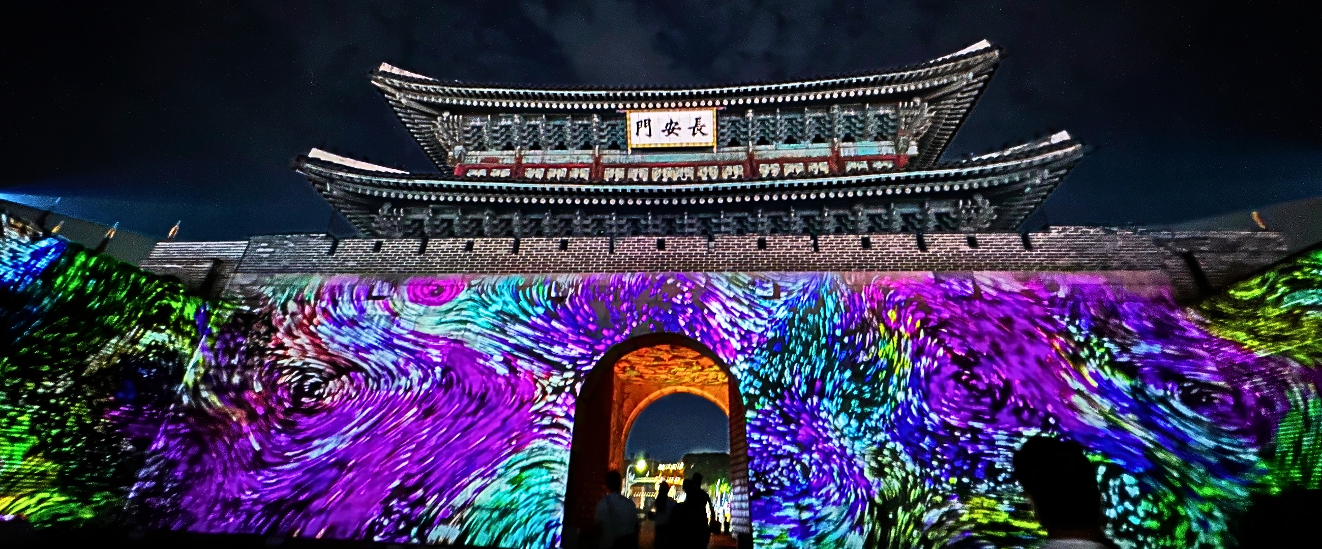 수원 화성 성곽을 스크린 삼아 펼쳐지는 화려한 미디어 아트 쇼. 다채로운 색의 조명과 패턴이 성벽을 가득 채우고 있다.