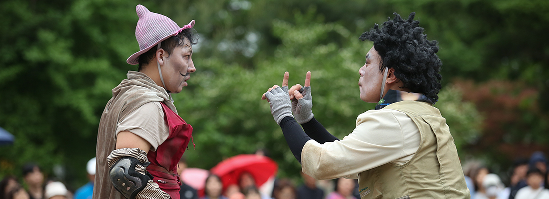 여러 공연자가 손에 눈같이생긴 부채를 들고 공연을 하고있다